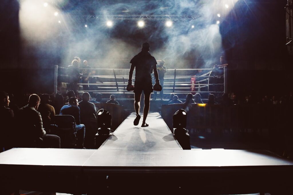 Lauren Price in a boxing ring wearing championship belts after unifying the welterweight division.