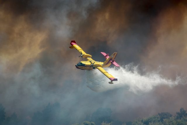 Aerial view of a wildfire approaching the outskirts of Fort McMurray, with smoke plumes rising above the boreal forest.