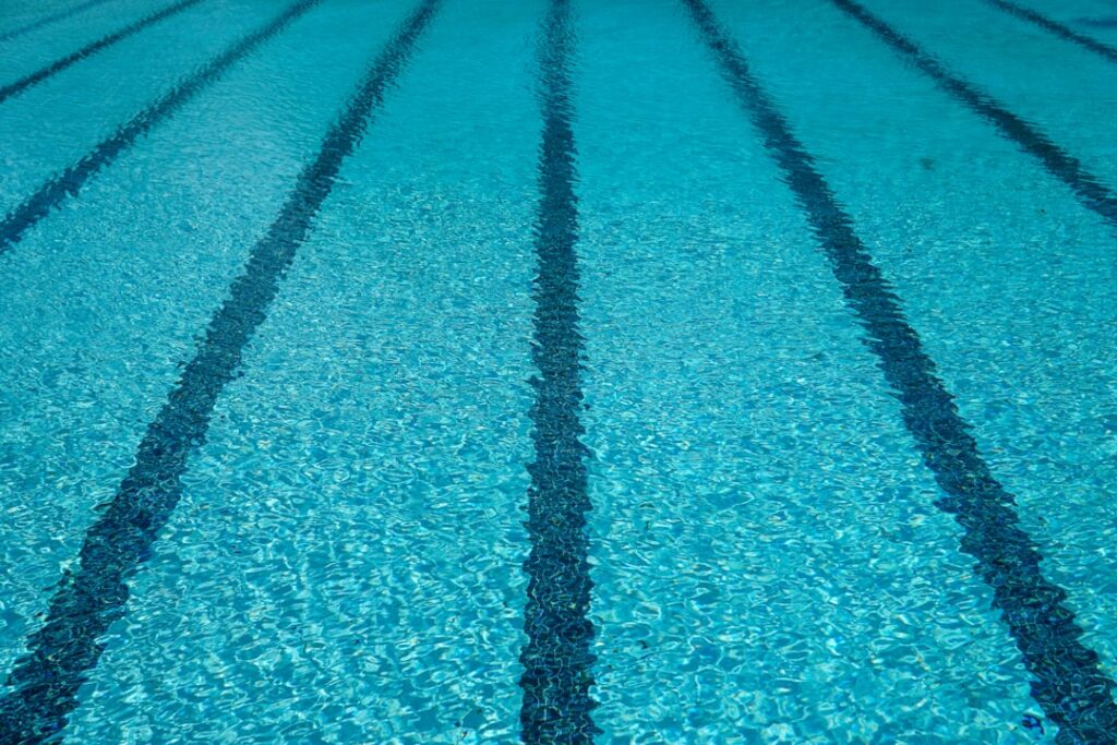 Paralympic swimmers race in a pool at the 2024 Paris Games, with spectators cheering from the stands.