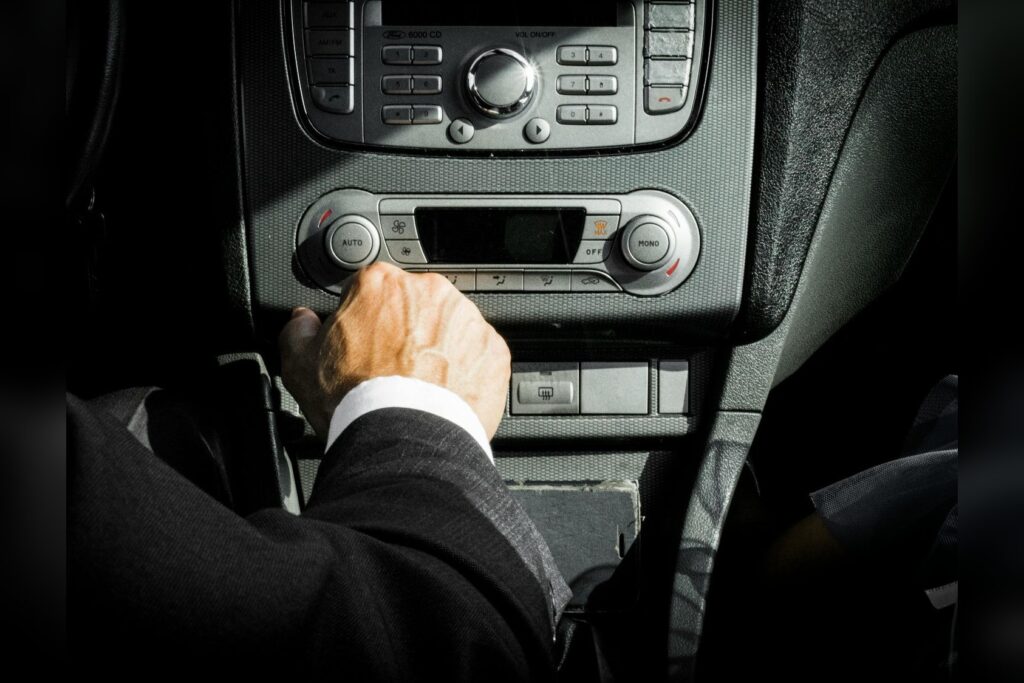 Driver Using Physical Buttons On A Car Dashboard